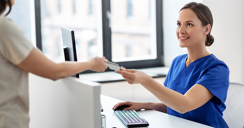 Medical worker at desk taking patient credit card