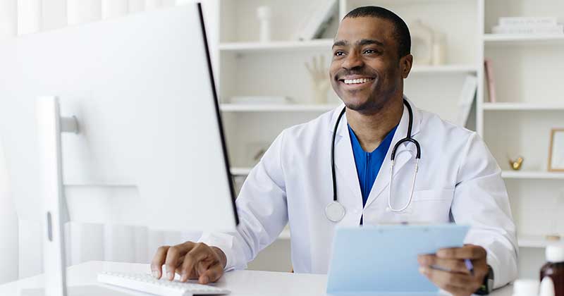 What to Look for in an EHR for Private Practice Doctor smiling with desktop