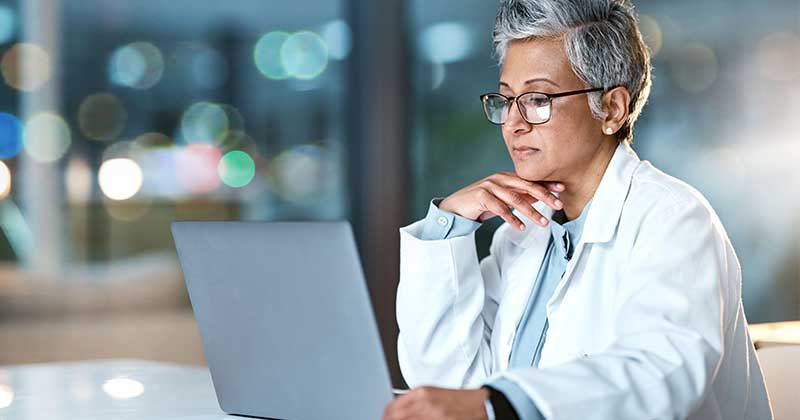Doctor wearing glasses working on a laptop