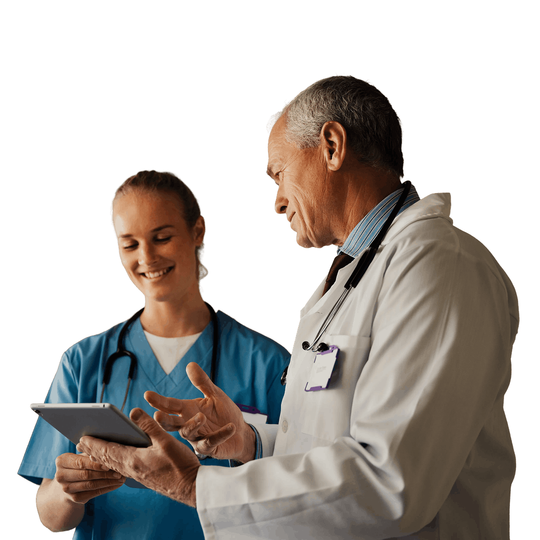 Doctor in white coat discusses information with nurse in blue scrubs, both looking at a tablet, against a plain background.