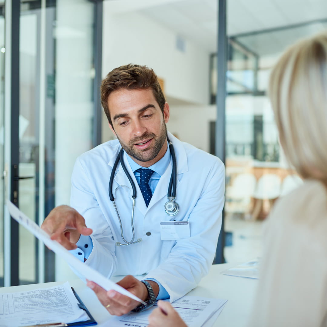 Doctor discussing paperwork with a patient in an office.