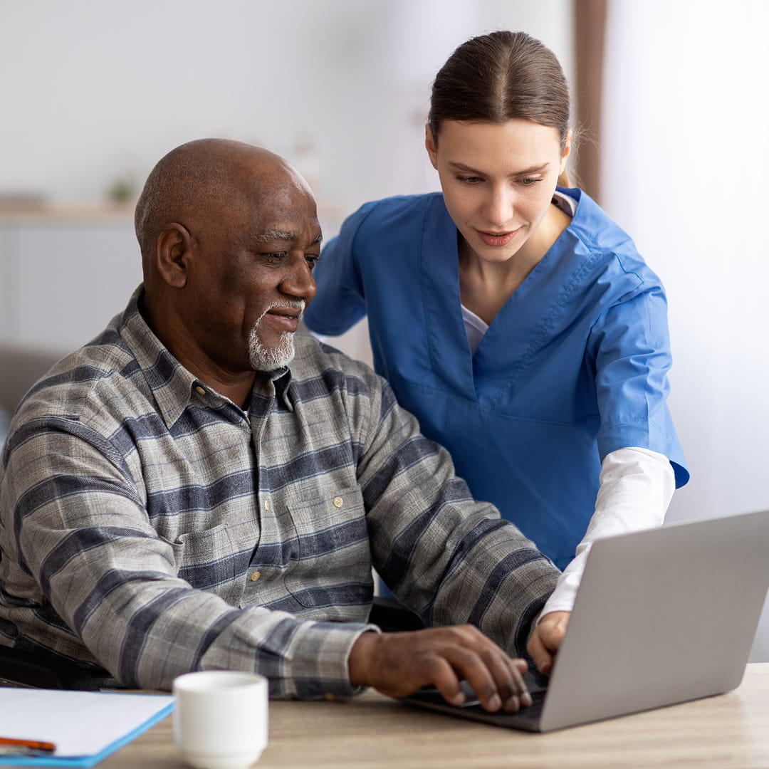 Doctor and elderly man sitting and smiling, discussing a document in a clinic setting.