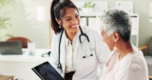 Mature woman, doctor and tablet for xray, support or conversation with cardiology checkup in office. Female person, medical professional and diagnosis talk for senior patient at clinic appointment.