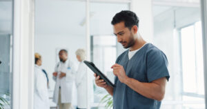 Doctor, tablet and research or planning schedule for healthcare, online medical consultation or search website. Asian man, nurse and reading report or patient analysis on tech device in hospital.