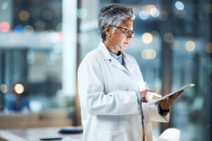 Hospital, tablet and senior doctor working online for medical report, planning and research in clinic. Technology, healthcare and woman with digital tech for telehealth, insurance and consultation.