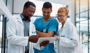 Doctor, team and tablet in healthcare planning for research, idea or meeting on technology at hospital. Happy group of doctors with touchscreen for medical data, collaboration or teamwork strategy.