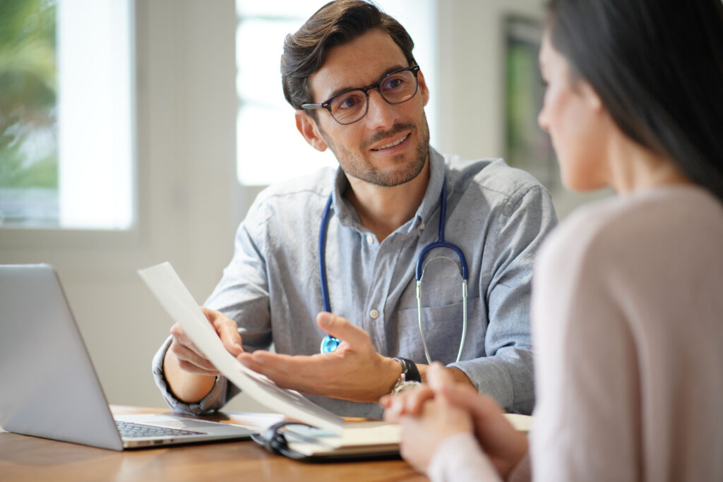 Modern young doctor speaking to patient in office